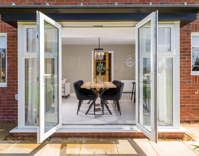 Glass pod with French doors opening onto a paved patio and large turfed garden