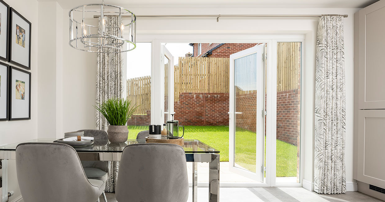 French doors opening onto a paved patio and large turfed garden