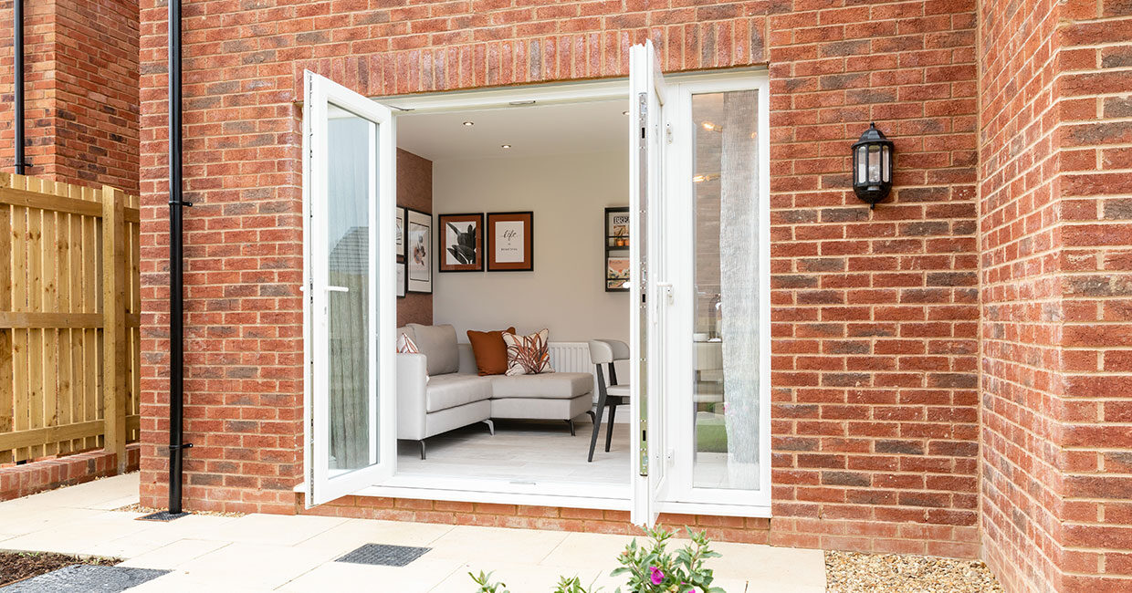 French doors opening onto a paved patio and large turfed garden