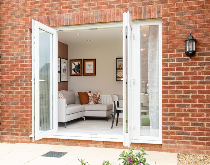 French doors opening onto a paved patio and large turfed garden