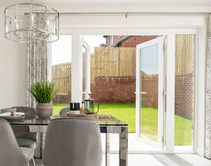 French doors opening onto a paved patio and large turfed garden