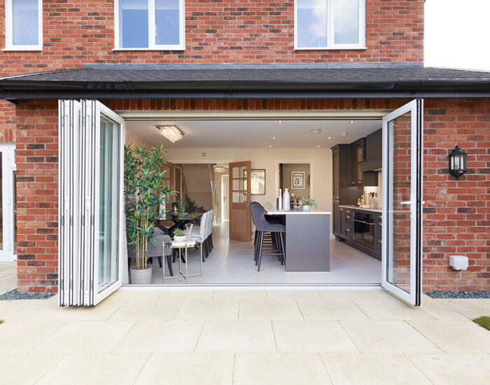 Bi-fold doors opening onto a paved patio and large turfed garden
