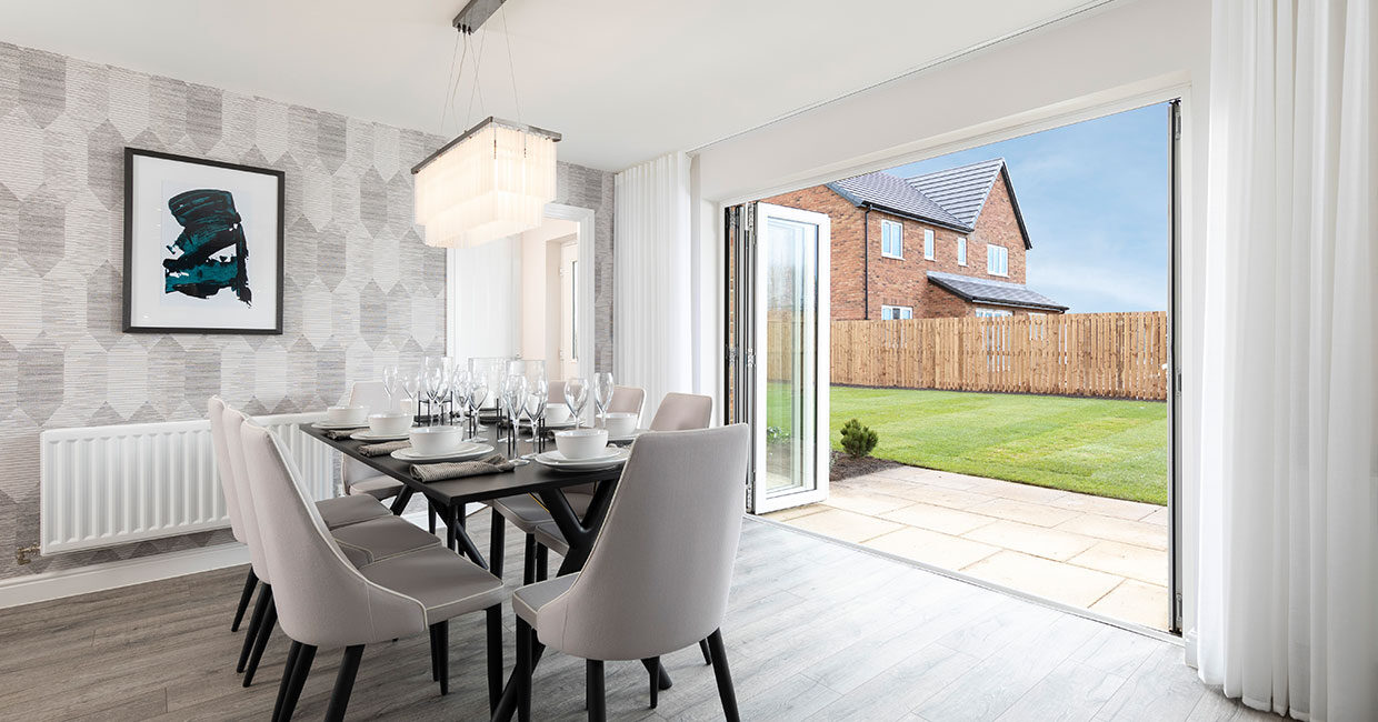 Bi-fold doors opening onto a paved patio and large turfed garden