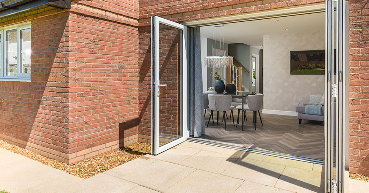 Bi-fold doors opening onto a paved patio and large turfed garden