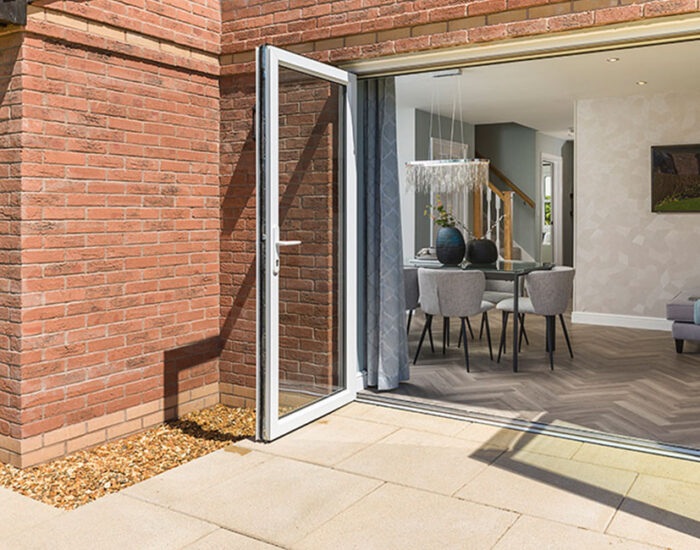 Bi-fold doors opening onto a paved patio and large turfed garden