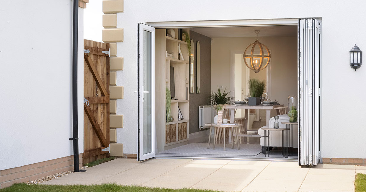 Bi-fold doors opening onto a paved patio and large turfed garden