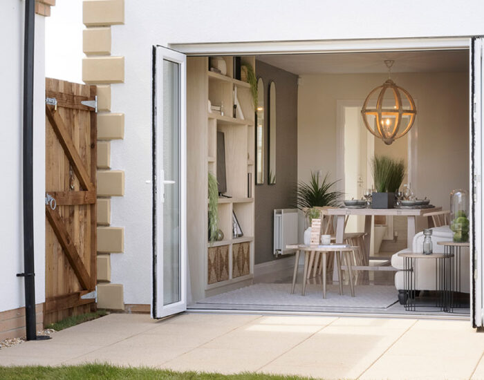 Bi-fold doors opening onto a paved patio and large turfed garden