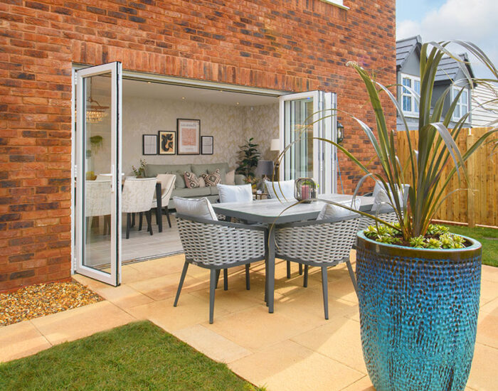 Bi-fold doors opening onto a paved patio and large turfed garden