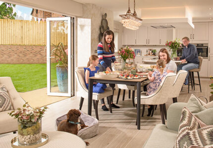 People in a Story home enjoying afternoon tea with the bi-fold doors open in the open plan kitchen, dining & family area of The Pennington house type