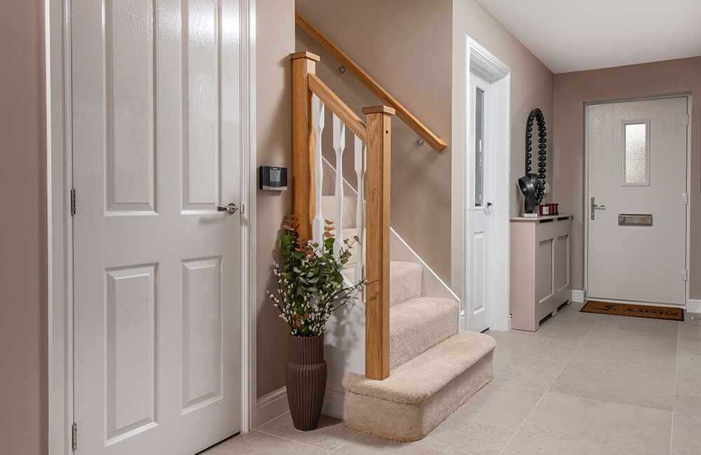 A view of the Hallway and bottom of the stairs in a Sanderson show home at Stonebrook Meadows, by Story Homes.