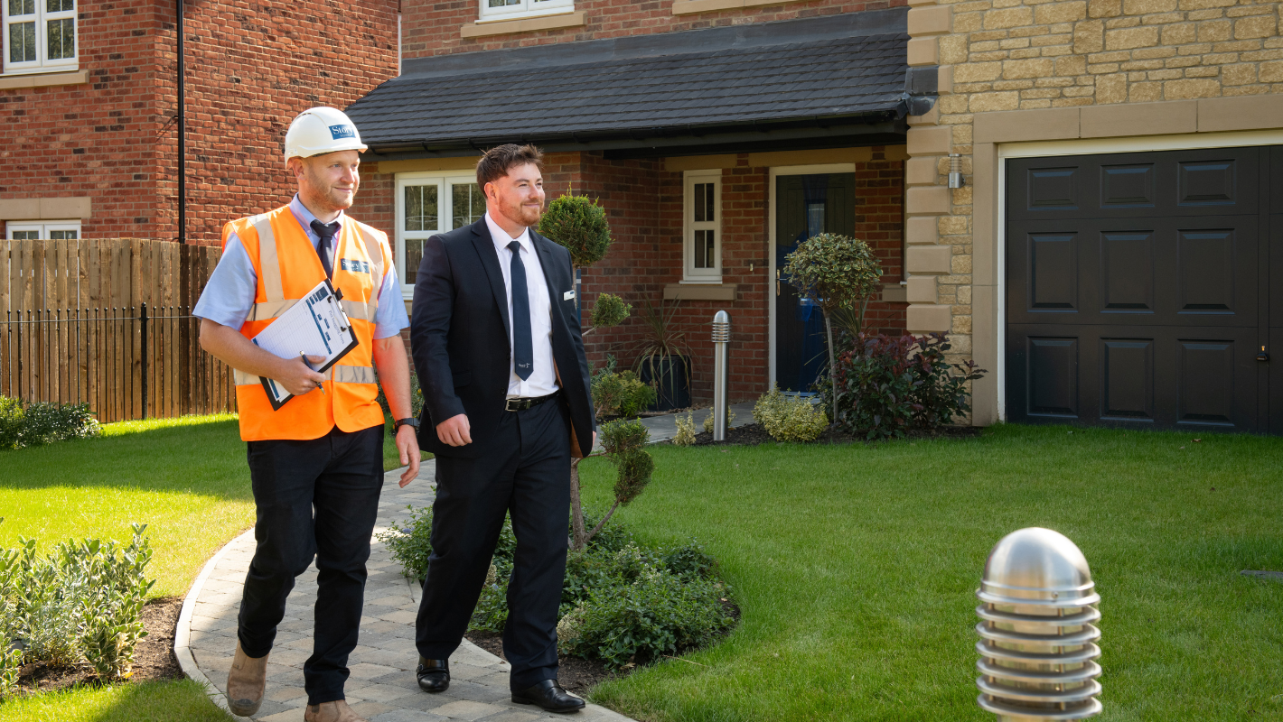 Site Project Manager and Sales Executive walking outside show homes